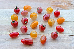 Colorful red, orange and yellow cherry tomatoes on wooden background