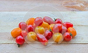 Colorful red, orange and yellow cherry tomatoes on wooden background