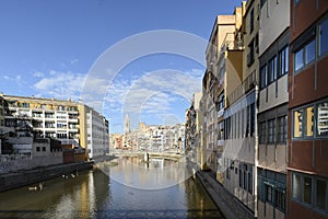 Colorful red, orange and yellow houses and bridge through river Onyar in Girona, Catalonia, Spain.