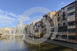 Colorful red, orange and yellow houses and bridge through river Onyar in Girona, Catalonia, Spain.