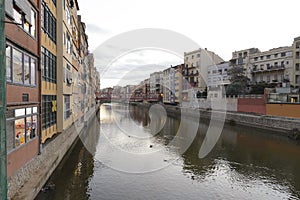 Colorful red, orange and yellow houses and bridge through river Onyar in Girona, Catalonia, Spain.