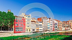 Colorful red, orange and yellow houses and bridge through river Onyar in Girona, Catalonia, Spain. Scenic ancient town. Famous