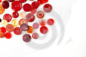 Colorful red and pink buttons on a white background. Lots of red buttons. Old vintage buttons close up. Copy space. Top view.