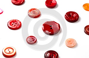 Colorful red and pink buttons on a white background. Set of red buttons. Old vintage buttons close up. Copy space. Side view.