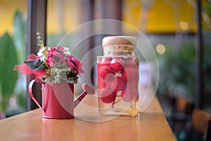 Colorful red rose flower in watering pot and cherries in glass