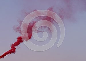 Colorful red smoke on a background of blue and pink sky