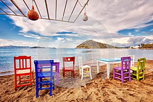 Colorful retro wooden chairs and a table lined up on the beach at the seaside