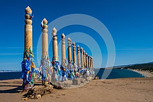 Colorful ribbons on the wooden pillars in sacred buryat place on cape Burkhan in Khuzhir village in Olkhon island, lake