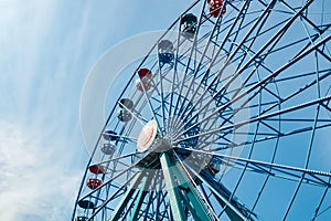 Colorful ride ferris wheel in motion in amusement park on sky background