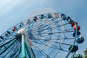 Colorful ride ferris wheel in motion in amusement park on sky background