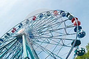 Colorful ride ferris wheel in motion in amusement park on sky background