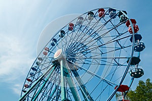 Colorful ride ferris wheel in motion in amusement park on sky background