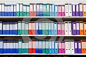 Colorful ring binder folder on white shelves