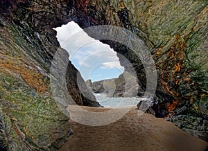 Colorful rocks in cave with sea and sky in background