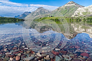 Colorful rocks on Driftwood Beach, with relfection of the Prince of Wales hotel in Waterton Lakes National Park Canada