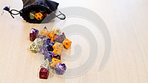 Colorful roleplaying dice scattered on a table with a linen pouch