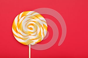 Colorful round Lollipop, on red background. Minimal concept with copy space