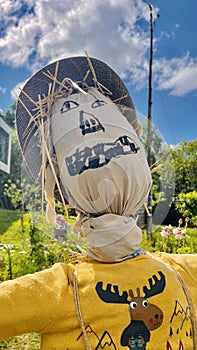 Colorful scarecrow outside near garden close up. Kids made looks funny