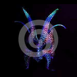 A colorful, scary halloween mask in blues and purples against a black background.