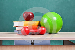 Colorful school accessories (apple, books, ball) on table