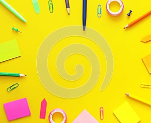 Colorful school items as a frame on yellow background