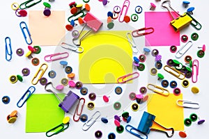 Colorful school and office supplies paper clips, pins, yellow notes, stickers on white background