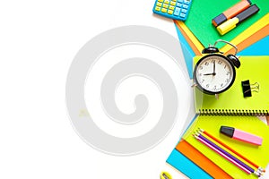 Colorful school supplies, book, and alarm clock on white. Top view, flat lay. Top view, copy space.