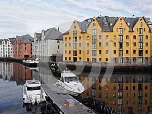 Colorful secessionist buildings of european Alesund town reflected in the water in Norway