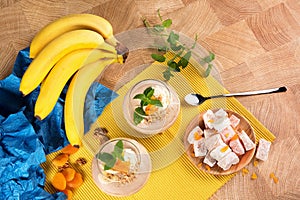 A colorful set of bananas, Turkish Delight, dried apricots, and sweet fruit desserts on a light wooden background.