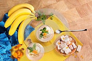 A colorful set of bananas, Turkish Delight, dried apricots, and sweet fruit desserts on a light wooden background.