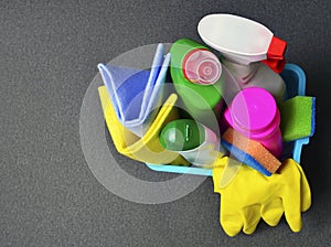 Colorful set of cleaning supplies in a blue basket with copy space.