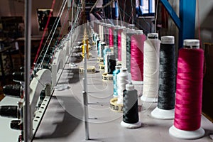 Colorful sewing thread rolls sitting on top of industrial embroidering machines