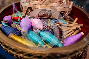 Colorful sewing thread spool on wooden basket.