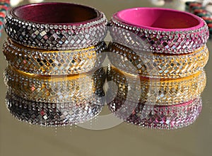 Colorful shiny Rajasthani bangles made up of glass and clay with reflection on mirror in soft focus
