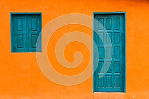 Colorful and Simple Orange Facade with Blue Greenish Door and Windows photo