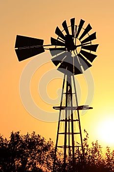 Colorful sky with  a windmill silhouette with orange and yellow sky in Kansas