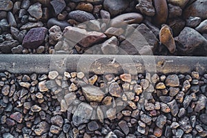 Colorful small pebbles and large stones divided by a curb at sunset