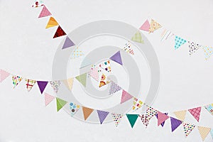 Colorful Small triangular decorative flags, pennons hangingon light wall background