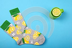 Colorful socks and herbal tea cup with lemon citrus fruits isolated on blue background