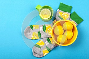 Colorful socks and herbal tea cup with lemon citrus fruits isolated on blue background