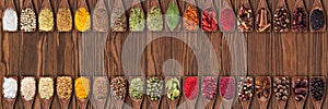 Colorful spices and herbs as element food packaging design. collection of condiments in wooden spoons on table  background