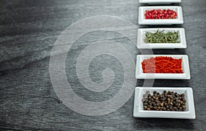 Colorful spices in white bowls on grey background. Seasonings for cooking. Copy space for text