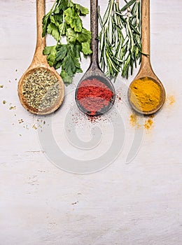 Colorful spices in a wooden spoon with herbs, tandoori, oregano, curry border ,place for text wooden rustic background top vie