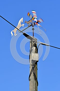 A colorful spinning pinwheel with a horse and a goat on a power pole as a symbol for wind energy