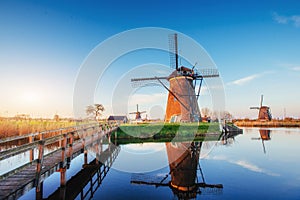 Colorful spring day with traditional Dutch windmills canal in Rotterdam. Wooden pier near the lake shore. Holland.