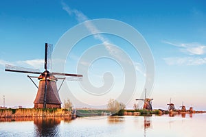 Colorful spring day with traditional Dutch windmills canal in Rotterdam. Wooden pier near the lake shore. Holland.