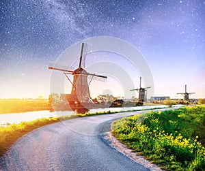 Colorful spring night with traditional Dutch windmills canal in Rotterdam. Wooden pier near the lake shore. Holland