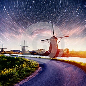 Colorful spring night with traditional Dutch windmills canal in Rotterdam. Wooden pier near the lake shore. Holland