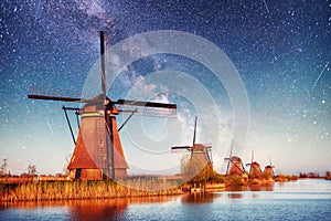 Colorful spring night with traditional Dutch windmills canal in Rotterdam. Wooden pier near the lake shore. Holland