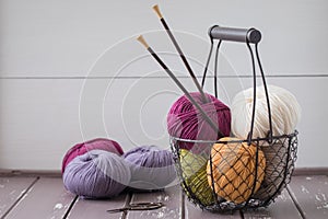 Colorful spring wool yarn in an iron basket with wooden knitting needles